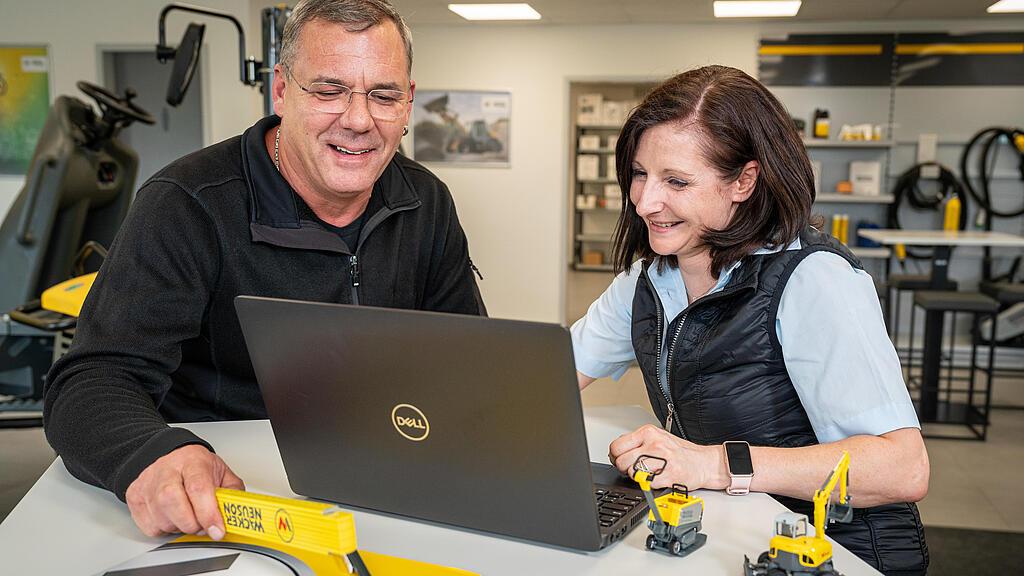 zwei personen beraten sich vor einem laptop