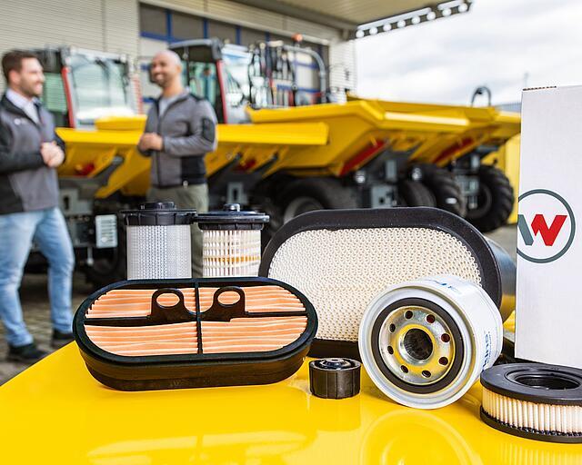 Wacker Neuson spare parts on Wacker Neuson construction machine, Wacker Neuson advisor, customer and construction machines in background.