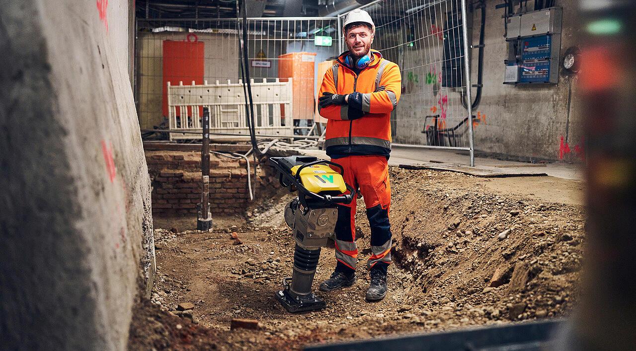 man standing next to battery powered rammer from wacker neuson at construction site