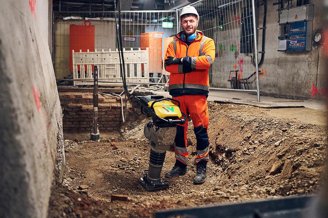 man standing next to battery powered rammer from wacker neuson at construction site